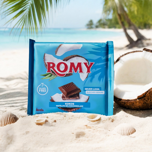 Bild von einer ROMY-Kokos-Schokolade, die am Strand vor Palmen und einer geöffneten Kokosnuss im Sand steht.